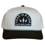 White and black baseball cap with a patch reading ’Fear is a Liar Zach Williams’.