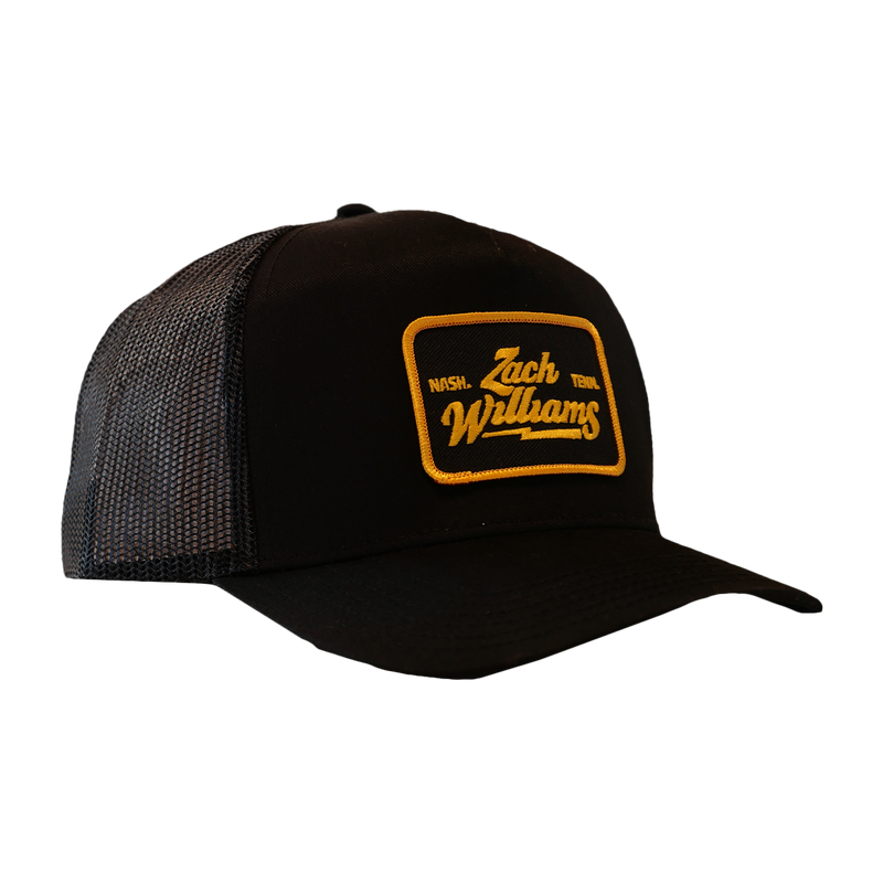 Black trucker-style cap with a yellow and orange ’Zach Williams’ patch on the front.