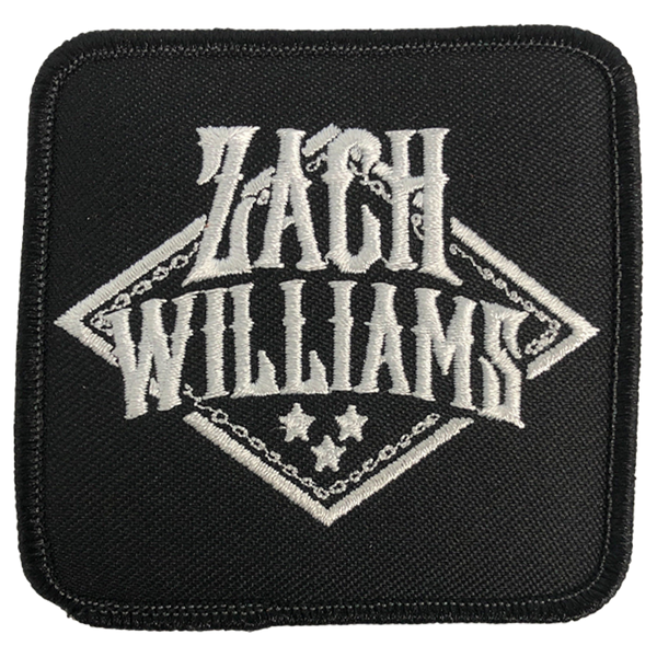 Black fabric patch with ’ZACH WILLIAMS’ embroidered in white lettering and decorative elements.